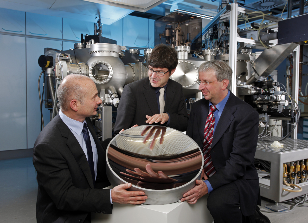 Together they develop essential components for EUV lithography: Dr. Torsten Feigl, Dr. Stefan Braun and Dr. Klaus Bergmann (f. l. to r.) with a collector mirror.